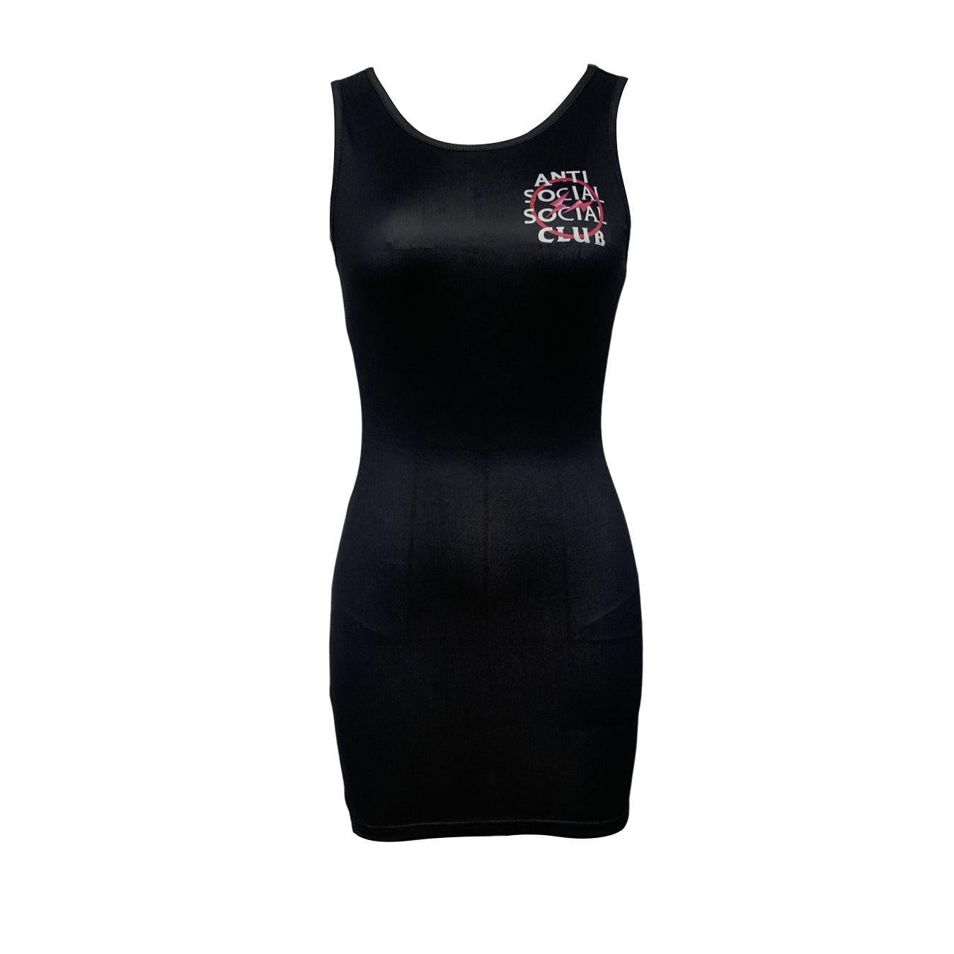 Woman wearing a black sleeveless bodycon dress with "Anti Social Social Club" graphic print on the back, standing by the sea at sunset.

