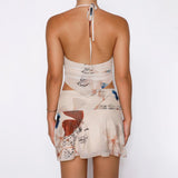 Woman wearing a red and white jacquard mini dress with floral patterns and side cutouts, posing on pink stairs in a summer setting.